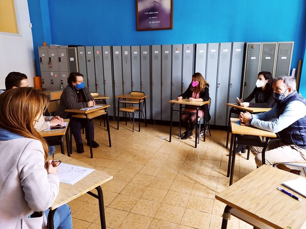 imagen de personas adultas, alguns políticos del PP de Castellón, dentro de un aula con mesas dispuestas en circulo y separadas