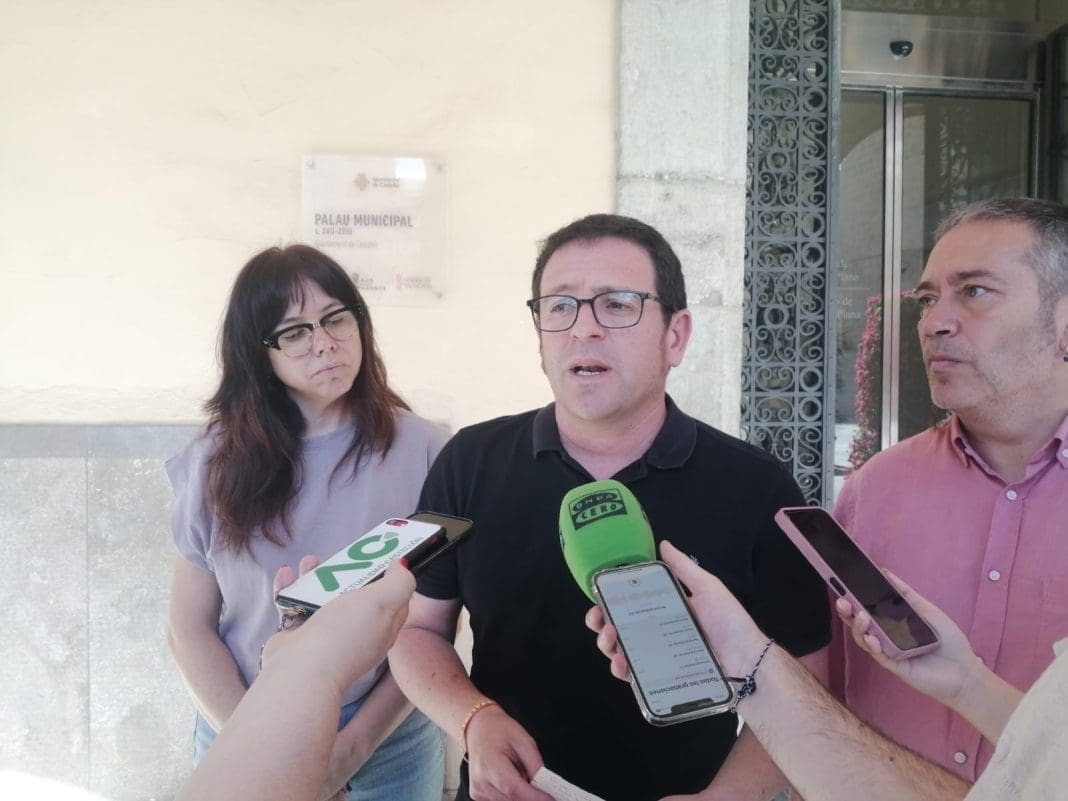 Imagen del protavoz de Compromís a las puestas del ayuntamiento de Castelón con micros delante mientras habla junto a dos compañeros de partido