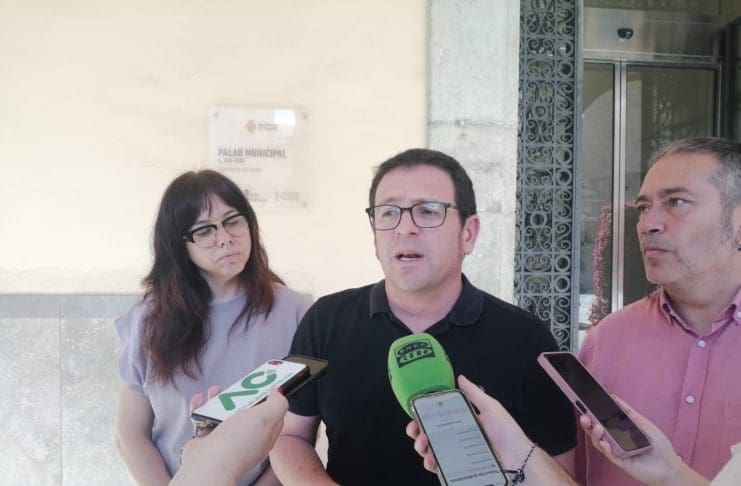 Imagen del protavoz de Compromís a las puestas del ayuntamiento de Castelón con micros delante mientras habla junto a dos compañeros de partido
