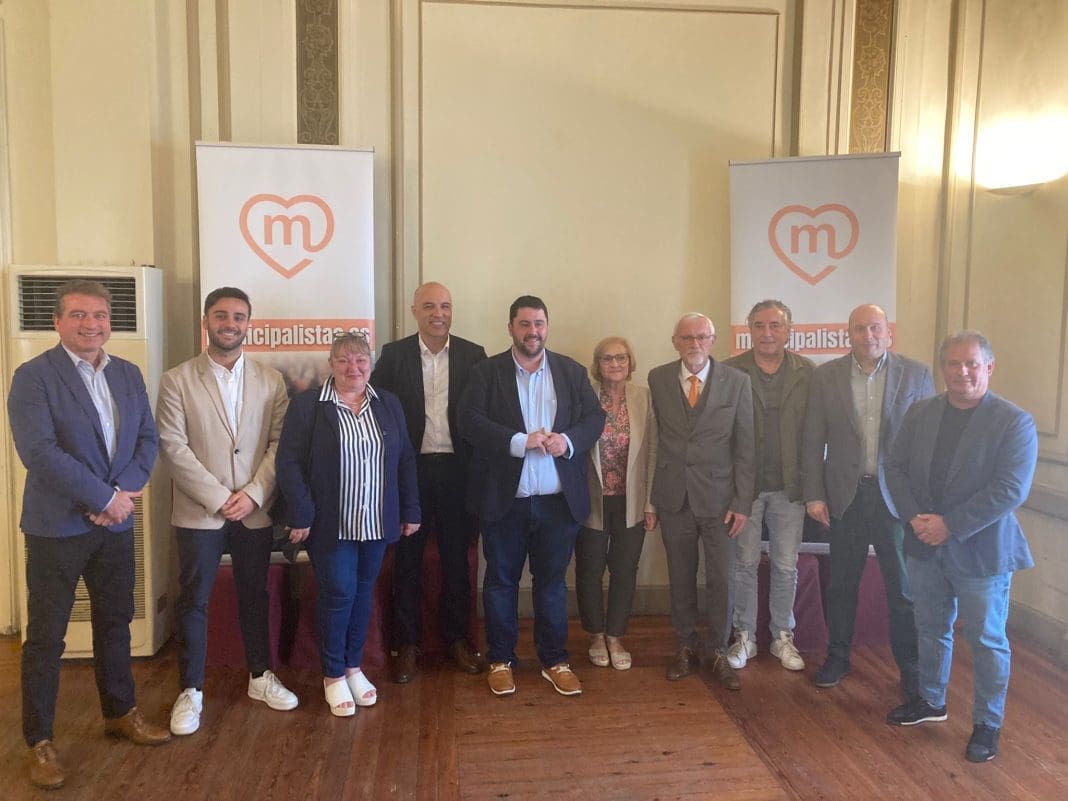 Imagen de algunos de los miembros de la Unión Municipalista en la provincia de Castellón posando con dos banderolas al fondo con el logo de la federación