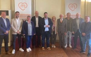 Imagen de algunos de los miembros de la Unión Municipalista en la provincia de Castellón posando con dos banderolas al fondo con el logo de la federación