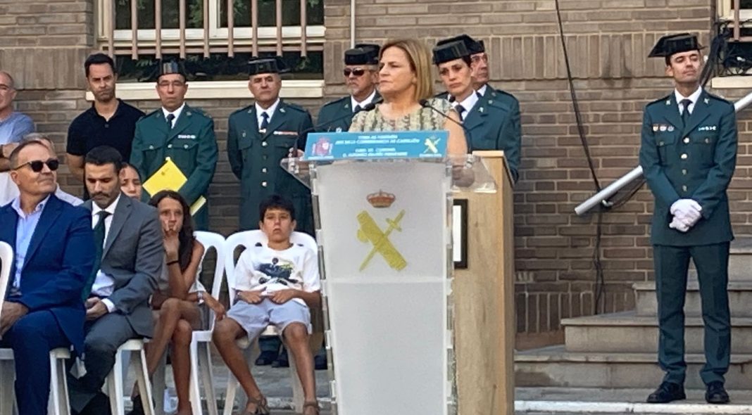 Pilar Bernabé hablando desde un atril con el logo de la Guardia Civil. Detrás de ella Guardia Civiles con uniforme de gala y en un lateral invitados sentados