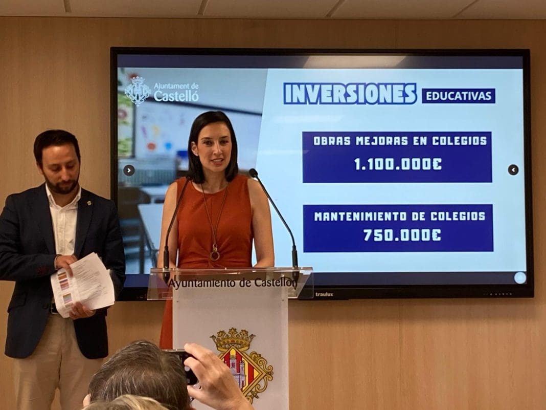 María España en un atril y detrás una pantalla mostrando la cifra de incersiones en centros educativos de Castellón y en su mantenimeinto. Al fondo, otro concejal, Sergio Toledo