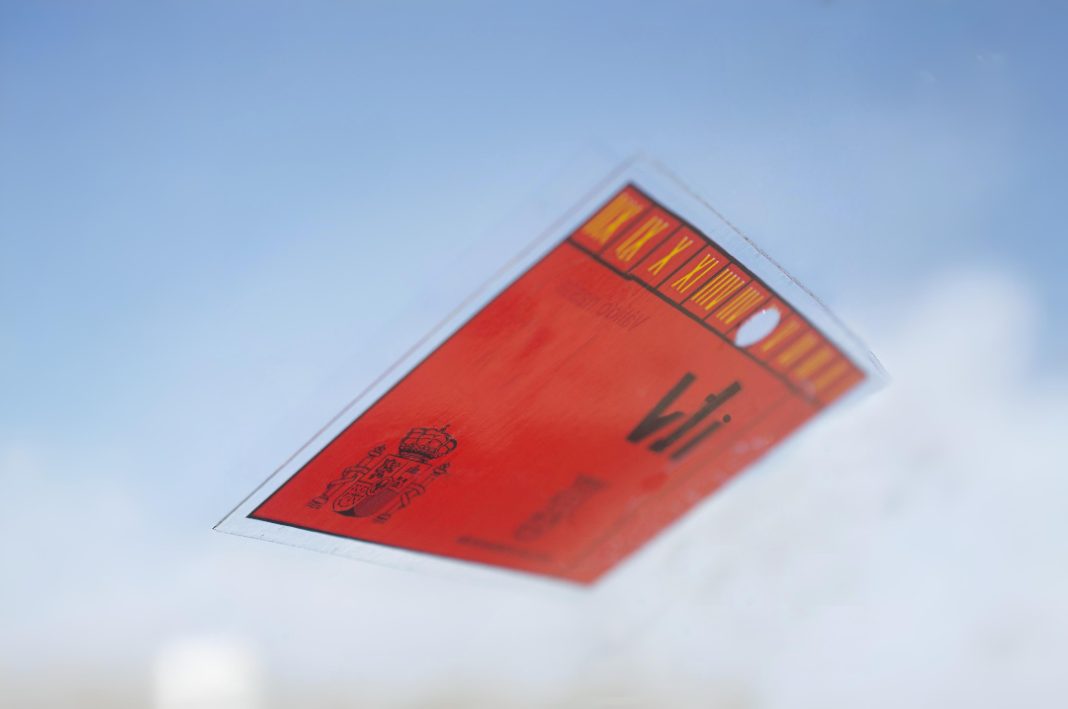 Pegatina de la ITV en Castellón color rojo en un parabrisas de coche