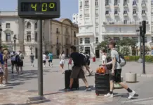 La Comunitat Valenciana se prepara para una semana de calor extremo y noches tropicales Turistas con maletas junto a un termómetro urbano que marca 40 grados en València
