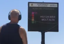 Ocho muertes por calor extremo en la Comunitat Valenciana en solo tres días Persona observa el cartel del índice ultravioleta en la playa de El Postiguet