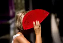 El calor da paso a un fin de semana más fresco en Castellón Mujer protege el sol con un abanico mientras se ven condiciones de calor en el exterior.